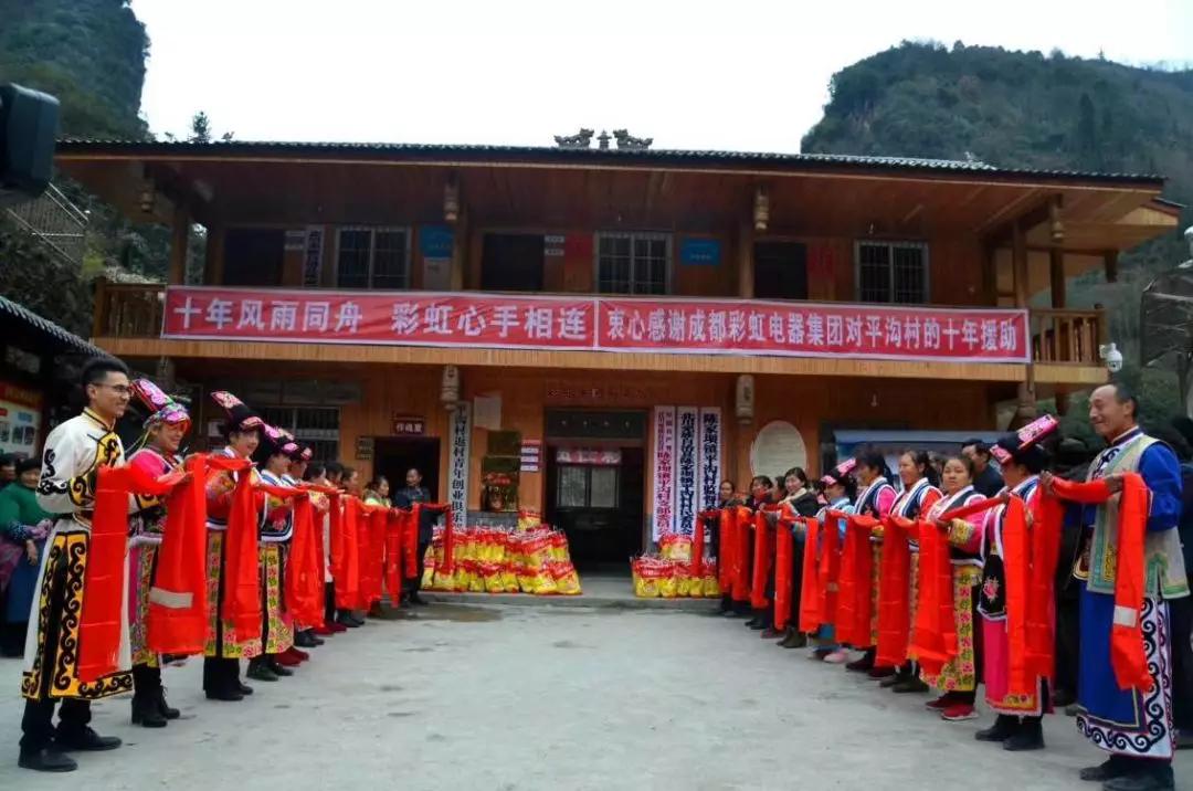 怀感恩之心，平沟村村民手持羌红在米兰（中国）公司援建的平沟村便民服务楼前热情等待米兰（中国）亲人们的到来